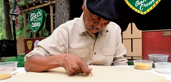 Older man wearing a beret while painting